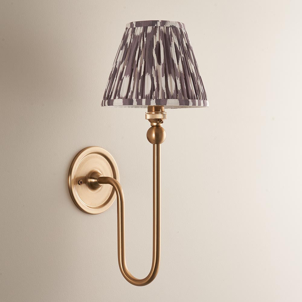 Cliffleigh Ikat Wall Light with brushed brass swan-neck arm and pleated grey and cream patterned fabric shade, mounted on a plain wall backplate.