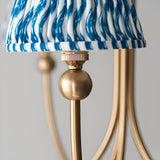 Close-up of the Endon Cliffleigh pendant showing a brushed aged brass curved arm, ball detail, and pleated marlin blue faux linen taper shade.