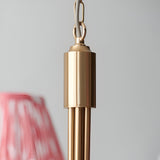 Close-up of the Cliffleigh 5-Light pendant's brushed aged brass frame, chain hook, and curved arms, with a blurred coral fabric shade.