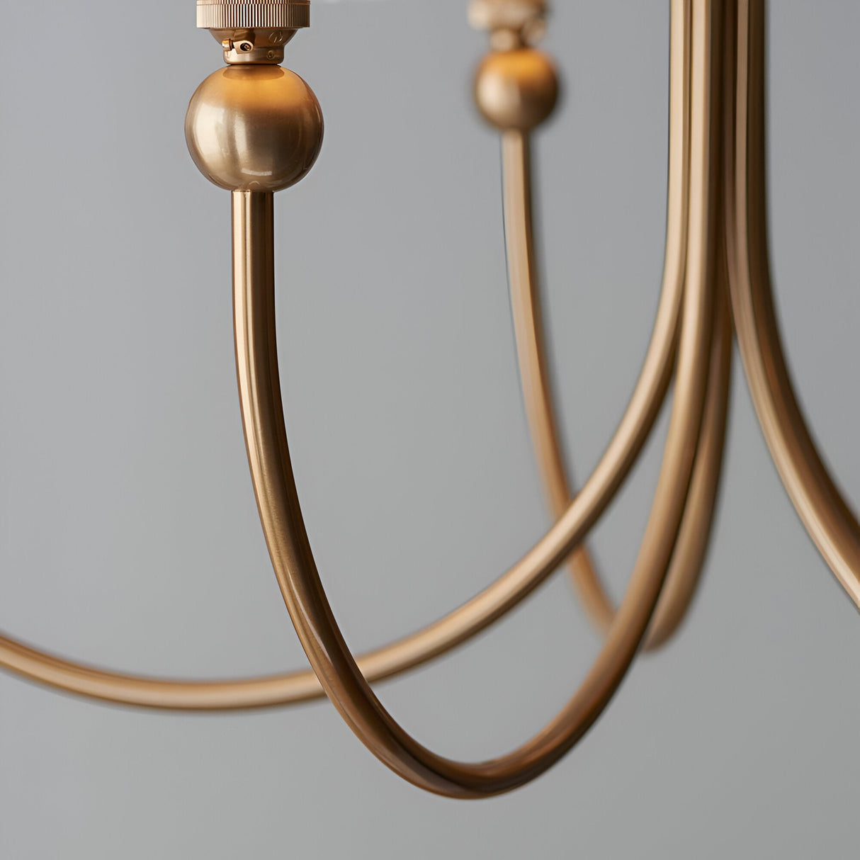 Close-up of the Cliffleigh 5 Light Curved Arm Ikat Pendant showing brushed aged brass curved arms and decorative ball joints against a plain grey background.