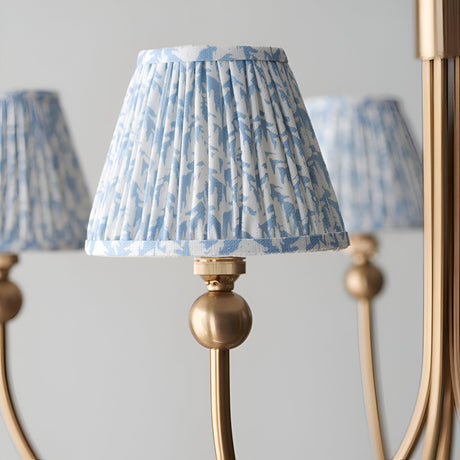 Close-up of Endon Cliffleigh Leaf pendant showing a tapered pleated shade in blue leaf print on faux linen, mounted on a brushed aged brass curved arm.