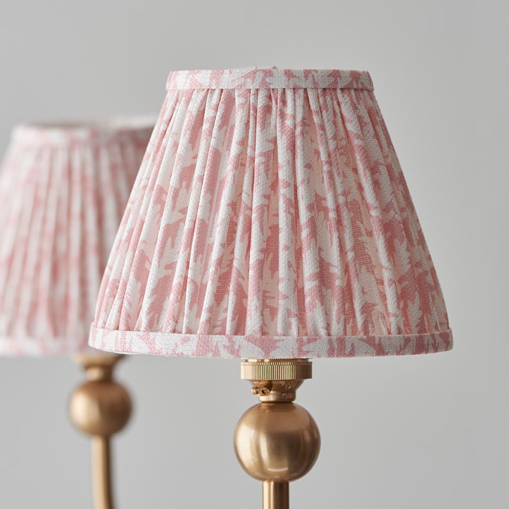 Close-up of Cliffleigh Leaf pendant light's tapered fabric shades in pink and white pattern, with brass gallery and ball fitting, on a light grey background.