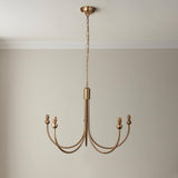 Cliffleigh Leaf 5-light curved arm pendant in brushed brass, hanging from a chain against a plain neutral wall.