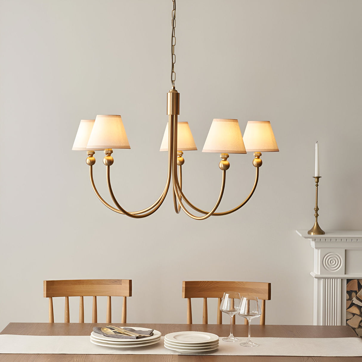 Cliffleigh 5 Light Curved Arm Pendant with brushed brass frame and white tapered fabric shades, hung above a dining table in a neutral-toned room.