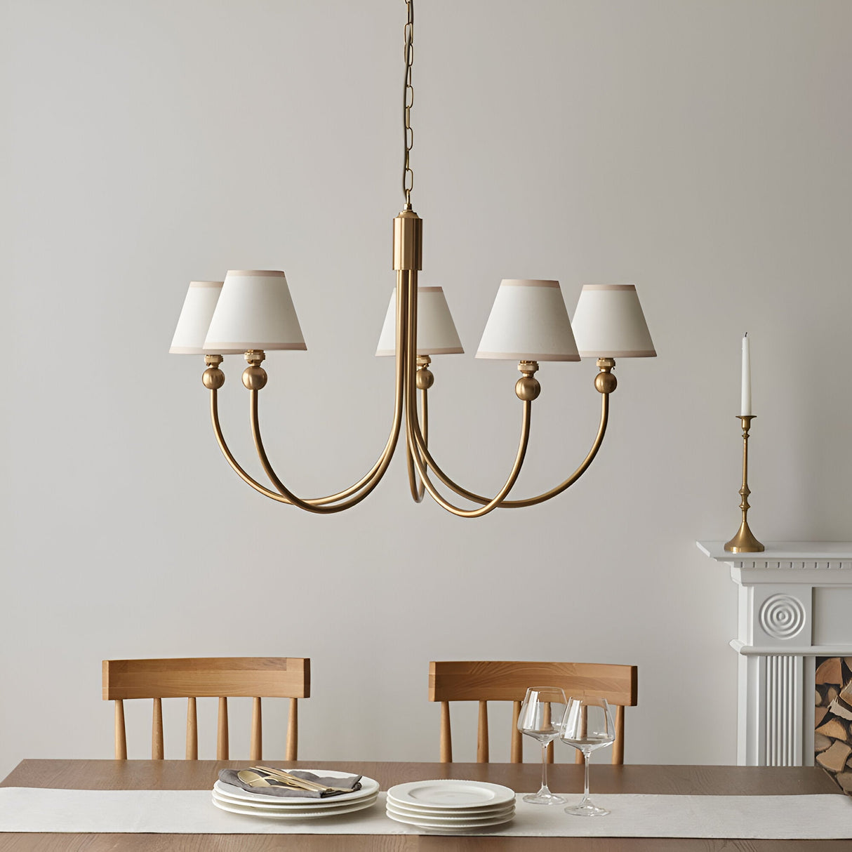 Cliffleigh 5 Light Curved Arm Pendant with brushed aged brass frame and tapered white fabric shades, shown above a dining table in a neutral-toned room.