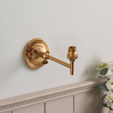 Endon Brackdon wall light in brushed aged brass with a rounded dome backplate, adjustable knuckle arm and B22 lampholder, mounted above panelled wainscoting.