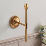 Endon Brackfield wall light in brushed aged brass with domed backplate, T-bar arm and B22 lampholder, mounted above panelled wainscoting.