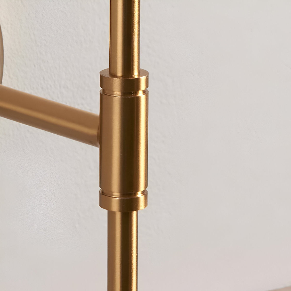 Close-up of the Endon Brackfield Wall Light showing the brushed aged brass T-bar arm joint and upright stem against a white wall.