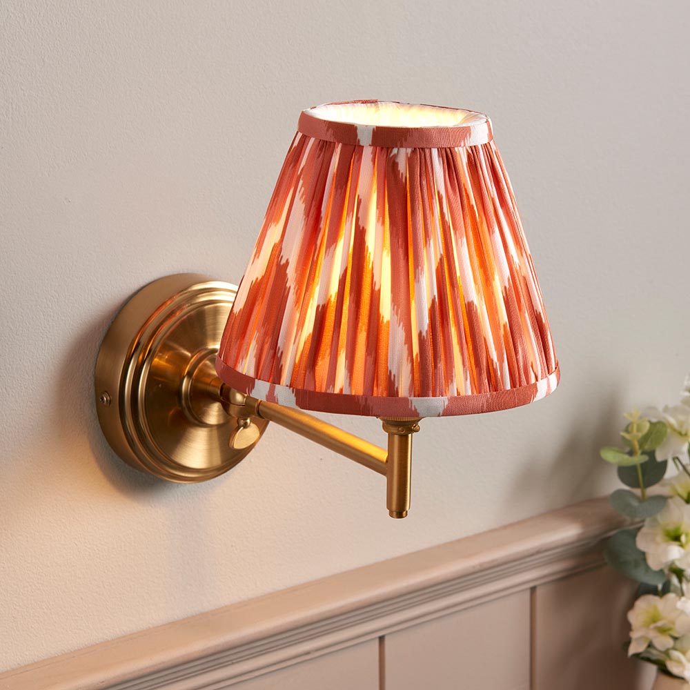 Endon Cliffwood wall light in brushed aged brass with adjustable knuckle arm and pleated red-and-white patterned fabric shade, mounted on a pale wall.