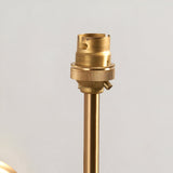 Close-up of the Endon Cliffworth wall light's brushed aged brass B22 lampholder and slim stem against a pale wall.