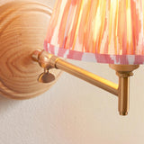Close-up of the Endon Daneley wall light showing its natural ash wood back, brushed aged brass adjustable knuckle, and linear arm against a white wall.