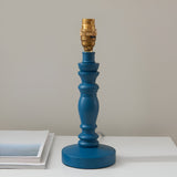 Endon Aldworth turned wooden spindle table lamp base in marlin blue with a brass B22 switched lampholder, shown on a white surface beside a book.