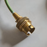 Close-up of the Endon Brackmont pendant's brushed aged brass B22 lampholder and green braided fabric cable against a light neutral background.