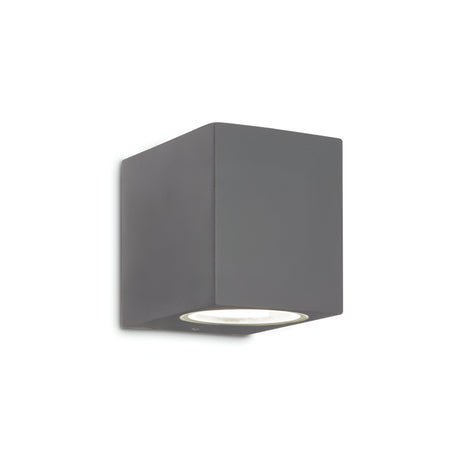 The Aethera Outdoor Wall Light in anthracite is a minimalist cubic fixture with a dimmable feature, mounted against a white background to provide versatile lighting.
