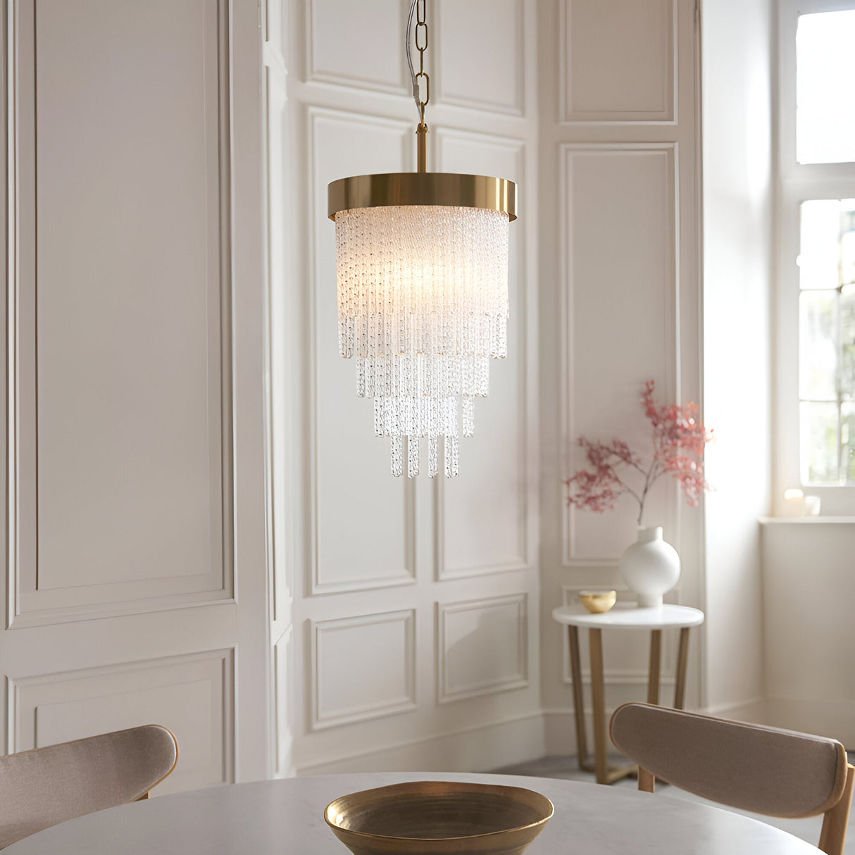 Aldfield Pendant in brass, a tiered fixture with twisted clear glass rods beneath a brushed aged brass frame, hung above a dining table in a panelled room.