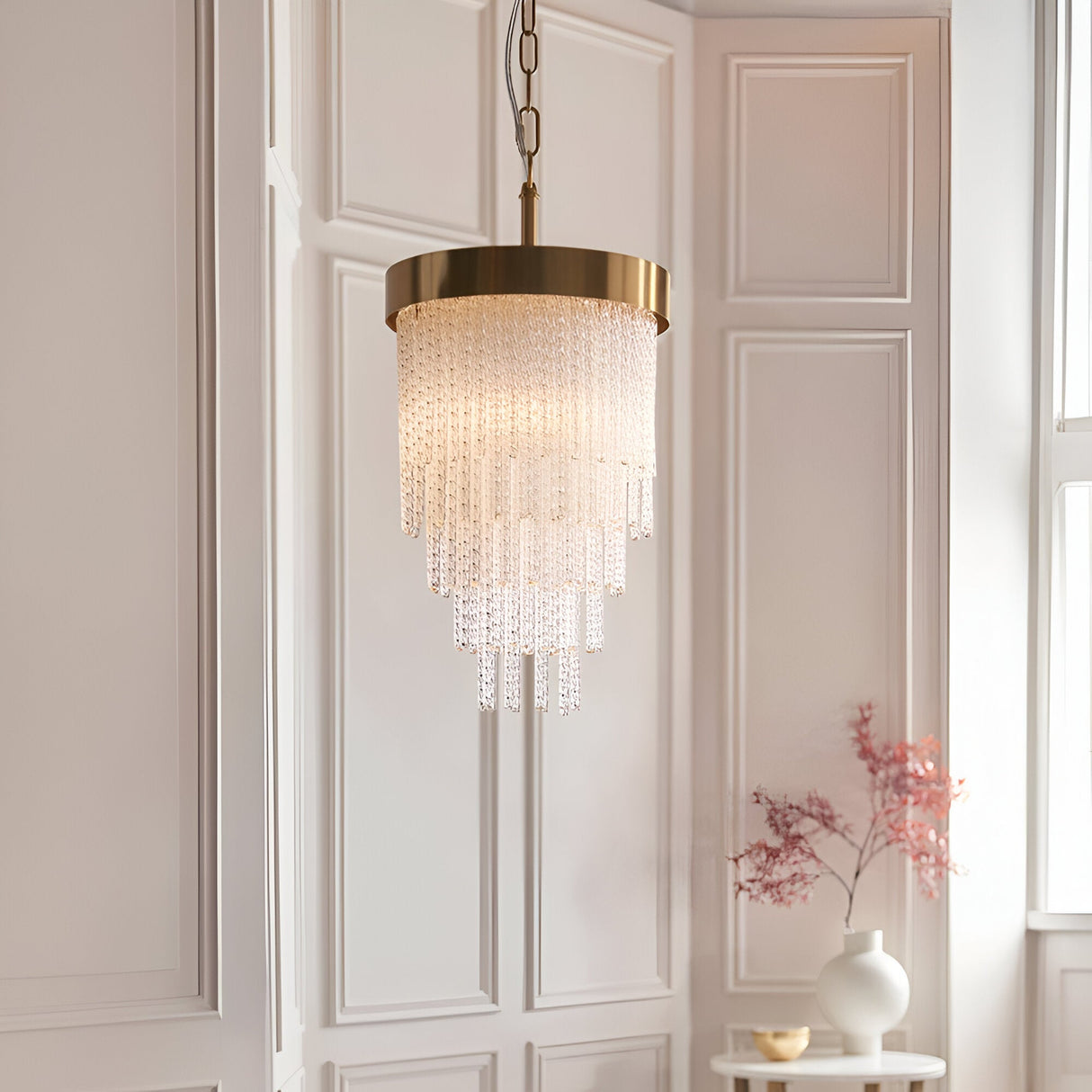Aldfield Pendant in Brass, a tiered single-light fixture with twisted clear glass rods beneath a brushed aged brass frame, hung in a panelled room.