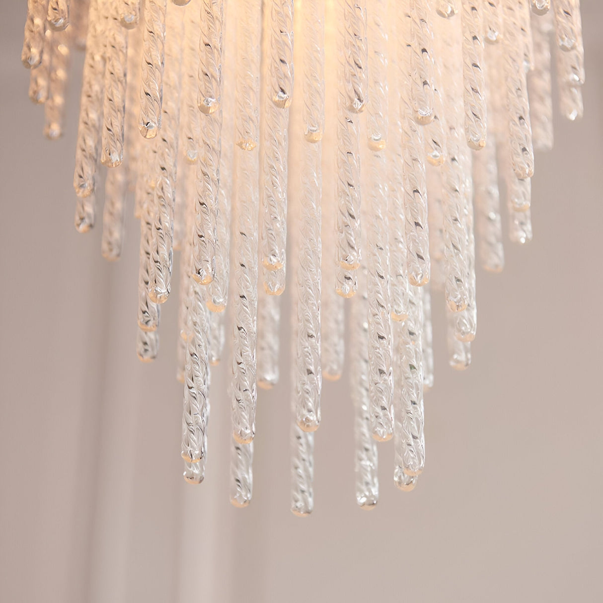Aldfield Pendant in Brass, close-up of tiered clear twisted glass rods cascading from a brushed aged brass frame, lit against a plain light background.