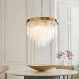 Endon Aldfield 5 light pendant with tiered clear glass rods and brushed aged brass frame, hanging above a marble dining table in a panelled room.