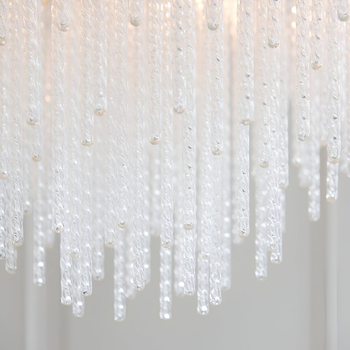 Close-up of the Endon Aldfield 5 Light Pendant showing tiered twisted clear glass rods with rounded tips, illuminated against a soft neutral background.