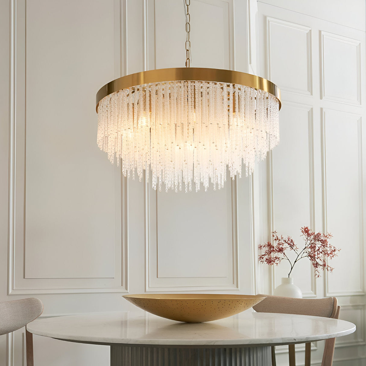 Aldfield 9 Light Pendant in brushed brass with tiered clear glass rods, hung above a marble dining table in a light-panelled room.