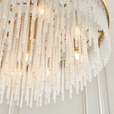 Close-up of the Aldfield 9 Light Pendant in brass, showing twisted clear glass rods layered in tiers on a brushed brass frame with visible bulbs.