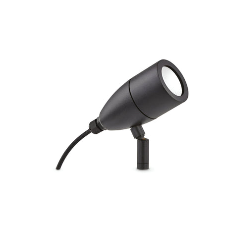 The Radiata Outdoor Single Spotlight in black features a sleek cylindrical design mounted on a short stand. This adjustable spotlight offers a weather-resistant fixture for outdoor durability and its movable head with an attached cable facilitates easy connection to a power source.