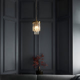 Endon Bevstead small single pendant with tiered clear glass lozenge drops on a brushed aged brass frame, hung in a dark panelled corner.