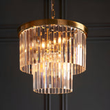 Bevstead 4 Light Pendant in brass with two-tiered cascading crystal glass rods, suspended by a chain against a dark panelled wall.