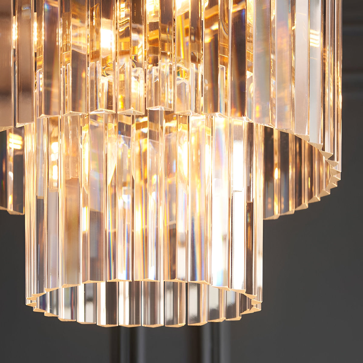 Bevstead 4-light pendant with tiered clear glass lozenge drops in a rounded cascade, set in a brass frame, shown in close-up detail.