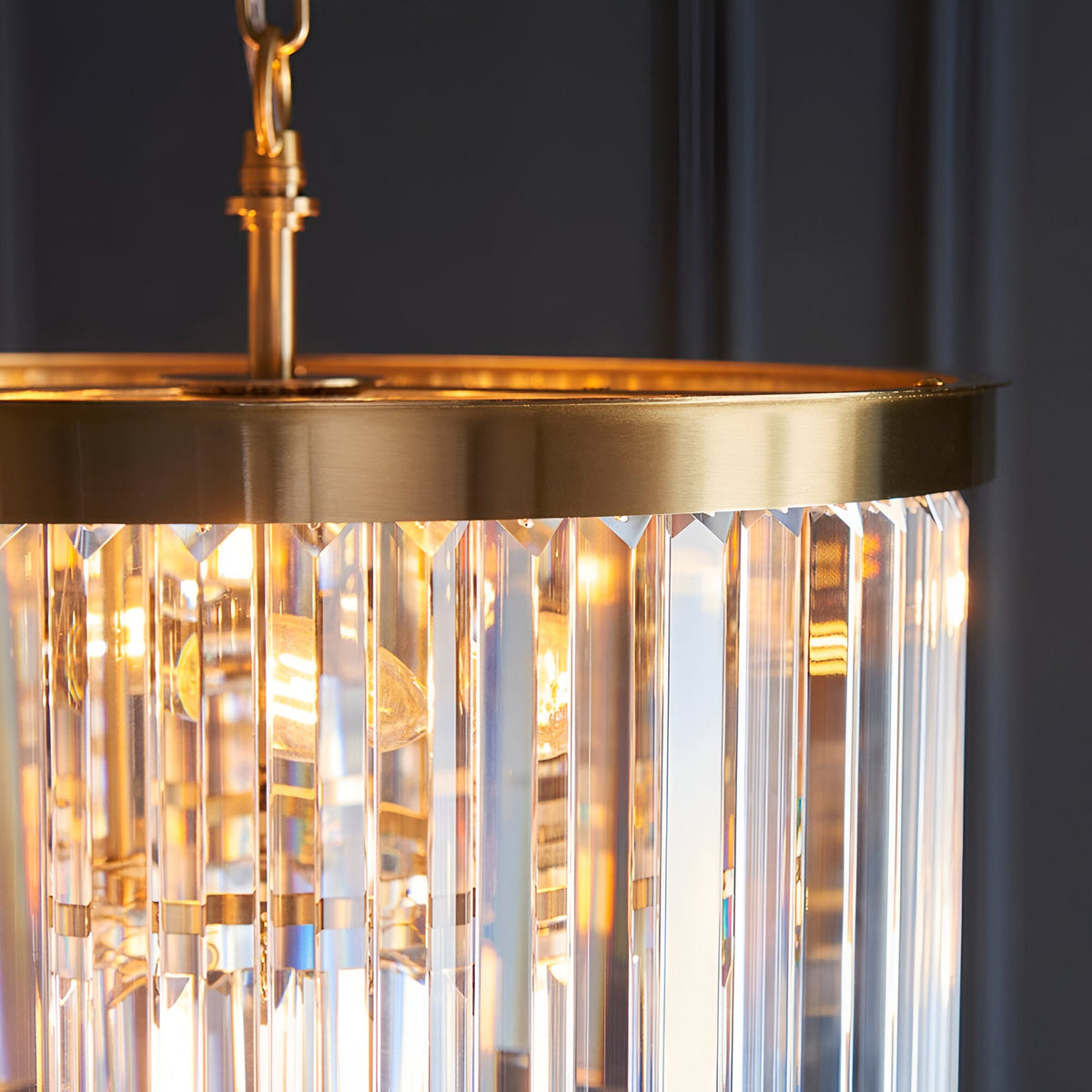 Close-up of the Bevstead 4 Light Pendant in brushed brass, showing the brass canopy edge and hanging crystal glass rods lit from within.