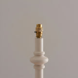 Close-up of the Endon Bevbury floor lamp's brass B22 switched bulb holder atop a white turned wooden spindle base against a neutral background.
