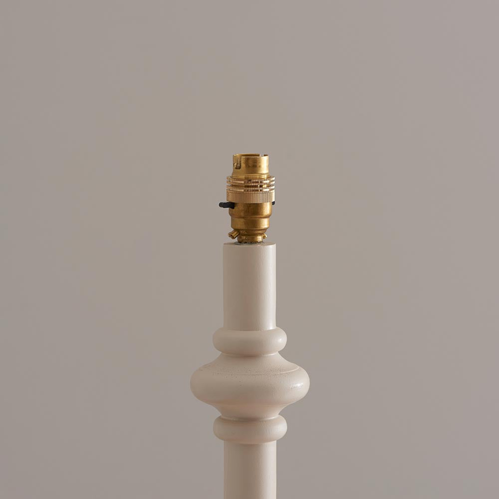 Bevbury Ikat Floor Lamp close-up showing white turned wooden spindle base with brass switched B22 lamp holder, against a plain neutral background.