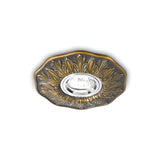 The Olivia Recessed Downlight in Antique Brass is a decorative ceiling fixture featuring a circular design with intricate patterns surrounding a central bulb, all set against a white background.