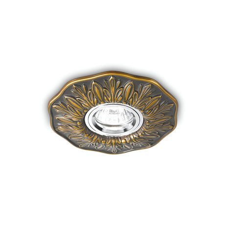 The Olivia Recessed Downlight in Antique Brass is a decorative ceiling fixture featuring a circular design with intricate patterns surrounding a central bulb, all set against a white background.