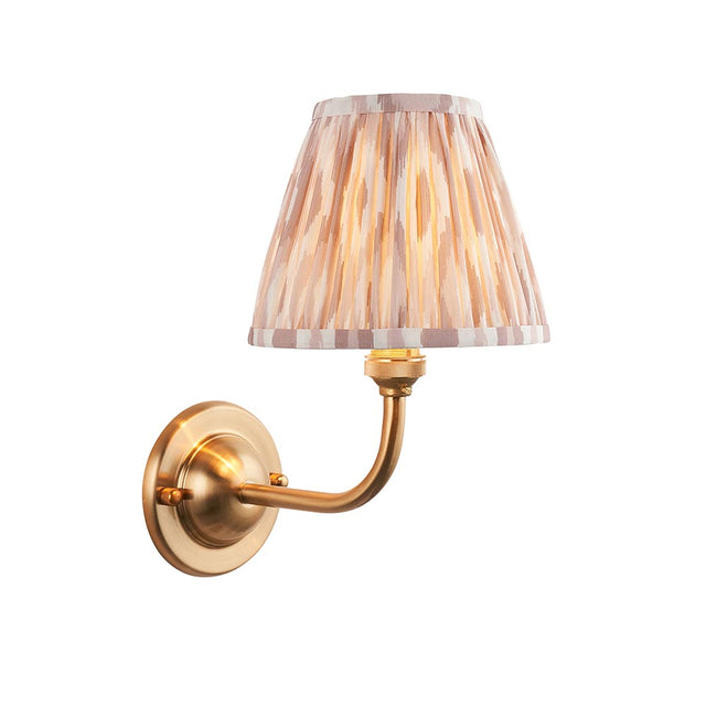 Endon Brackdale Ikat wall light with brushed aged brass curved arm and pleated natural Ikat-print fabric shade, shown on a plain white background.