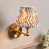 Endon Corven wall light with brushed brass stepped base, adjustable arm, and tapered pleated shade in grey Ripple print on faux linen.