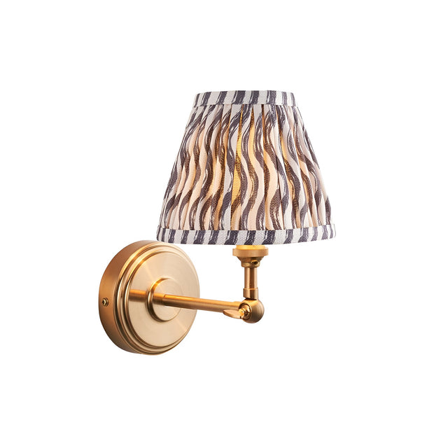 Endon Corven wall light in brushed brass with adjustable arm and pleated grey Ripple pattern faux linen shade, shown on a plain white background.