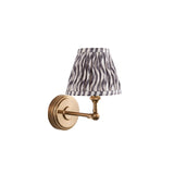 Endon Corven wall light with brushed aged brass adjustable arm and pleated grey Ripple pattern fabric shade, shown on a plain white background.
