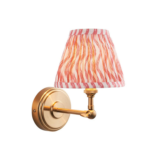 Corven Wall Light in brushed brass with adjustable knuckle arm and pink Ripple-pattern fabric shade, shown on a plain white background.