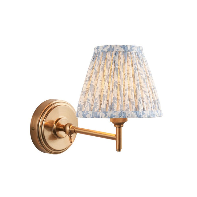 Endon Cliffwood Leaf wall light with brushed aged brass stepped backplate, adjustable arm and pleated blue leaf-print fabric shade on a white background.
