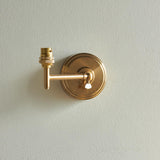 Endon Cliffwood Leaf wall light base in brushed aged brass, with stepped backplate, linear arm, adjustable knuckle and B22 lamp holder, on a light grey wall.