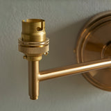 Close-up of the Cliffwood wall light's brass B22 lamp holder and adjustable knuckle arm with circular wall backplate, shown against a plain light background.