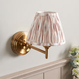 Cliffwood Ikat Wall Light with brass adjustable arm and pleated pink-and-white patterned fabric shade, mounted on a light grey wall.