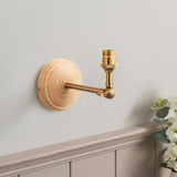 Endon Danemere wall light with natural Ash wood backplate, brushed aged brass adjustable arm and B22 lamp holder, shown unshaded on a grey wall.