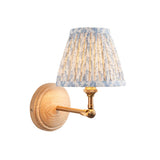 Danemere wall light with a natural Ash wood backplate, brushed brass arm, and pleated leaf-print fabric shade in blue and cream, shown on a white background.