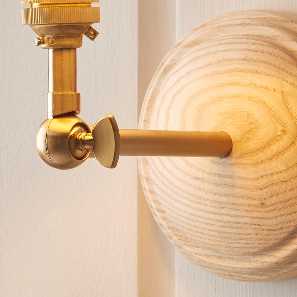 Danemere Wall Light close-up showing brushed brass arm with adjustable knuckle joint against a round natural Ash wood wall back.