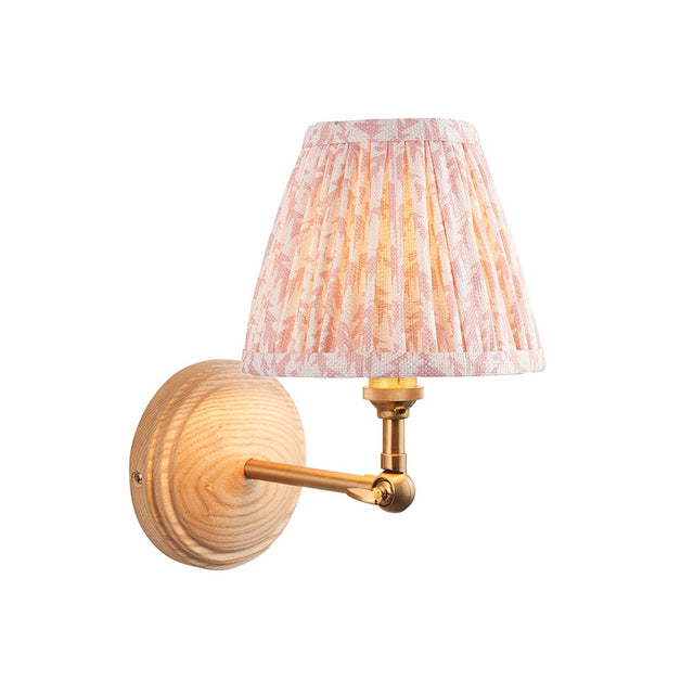 Endon Danemere wall light with natural Ash wood back, brushed brass adjustable arm, and pleated peach Leaf-print faux linen shade on a white background.