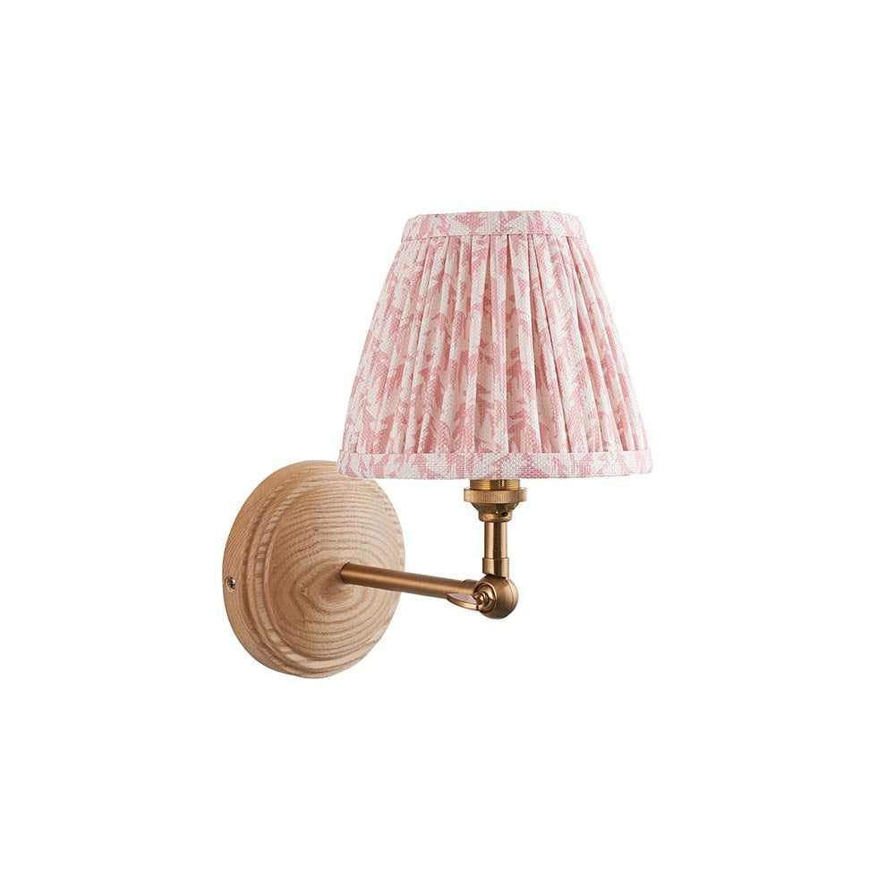 Endon Danemere wall light with natural Ash wood back, brushed aged brass adjustable arm, and pleated pink leaf-print faux linen shade on a white background.