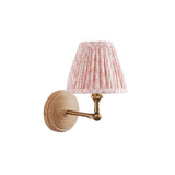 Endon Danemere wall light with natural Ash wood back, brushed aged brass adjustable arm, and pleated pink leaf-print faux linen shade on a white background.