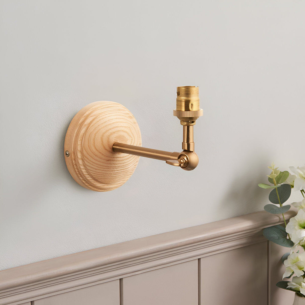 Endon Danemere wall light with natural ash wood back plate, brushed aged brass adjustable arm and B22 lamp holder, shown unshaded on a light grey wall.